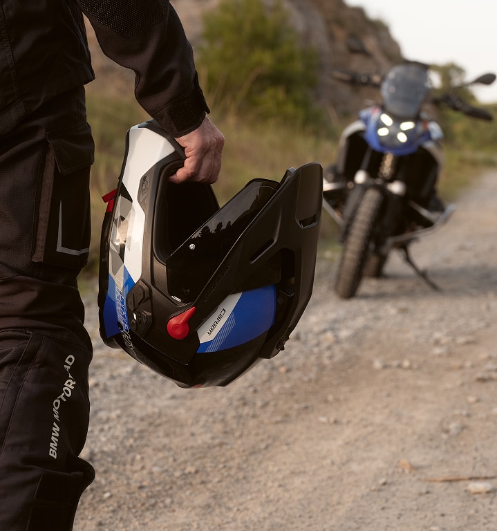 Egy személy egy motoros sisakot tart a kezében.